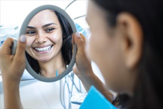 Reflection of a beautiful woman looking in the mirror at the dentist's office. Concept of whitening