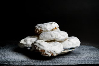 Sugar glazed donuts on a blue plate covered with icing sugar on a black background and copy space