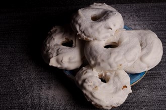 Sugar glazed donuts on a blue plate covered with icing sugar on a black background and copy space