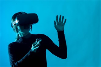 Metaverse technology concept. Woman in virtual reality VR glasses on a blue background. Futuristic