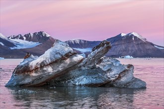 Ice berg shape Kongsfjorden in a unique abstract shape in the beautiful colorful sunrise light of the Arctic. Behind mountains of Svalbard Archipelago