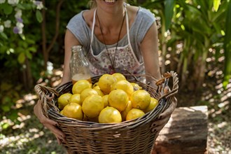 A woman carrying a wicker basket full of fresh lemons