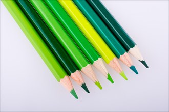 Color Pencils of various tones of green color on a white background