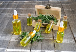 Dropper bottles with rosemary essential oil in a wooden box on a wooden table