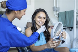 A patient smiles and looks into a mirror while being seen by the dentist