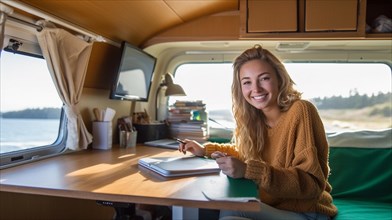 Happy young adult female enjoying working remotely inside her RV camper trailer