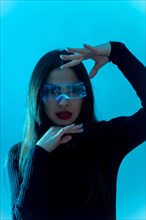 Metaverse technology concept. Woman in futuristic glasses with led light on a blue background