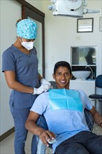 Female dentist in dental office talking with young male patient and preparing for treatment
