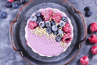 Fruit smoothie bowl with pink yogurt decorated with healthy raspberry
