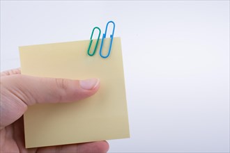 Hand holding a notepaper with paper clips on a white background