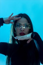 Metaverse technology concept. Woman in futuristic glasses with led light on a blue background. Futuristic