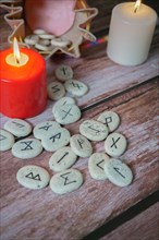 Viking stone runes emerging from his pink leather sack with two candles on a wooden table