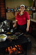 Mature latin woman cooking looks at the camera and smiles