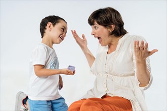 A little boy surprises his mother with a gift. Mother's day concept. Mum's birthday. Studio image with white background