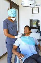 Portrait of dentist with his patient looking at each other in dental office. Concept of whitening