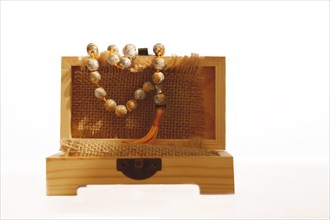 Close-up of a wooden box with a Buddhist japa mala wrapped in a raffia cloth isolated on a white background