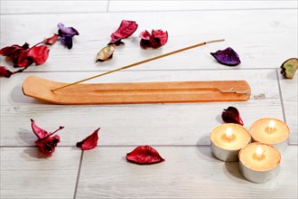 Close-up of an incense stick isolated on a white background with colorful flower petals and yellow candles