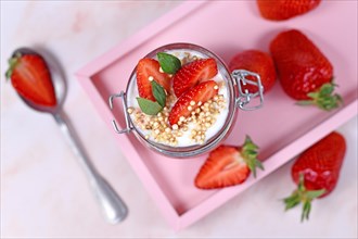 Top view of healthy strawberry fruit dessert with yogurt and puffed quinoa grains on pink tray
