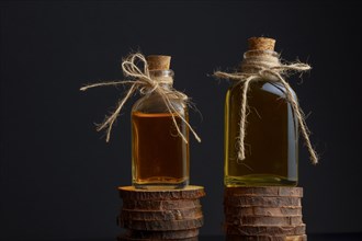 Glass bottles with olive oil on wooden discs isolated on black background and copy space