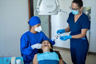Young female dentist and female assistant attending to patient