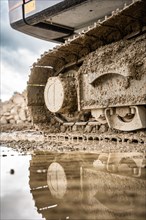 Tracked excavator in dirt with puddle