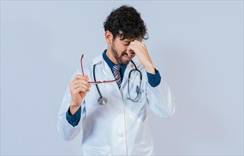 Overworked doctor with eyestrain isolated. Doctor holding glasses with burning eyes
