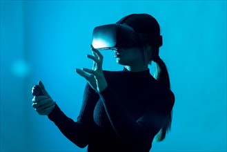 Metaverse technology concept. Woman in virtual reality VR glasses on a blue background. Futuristic lifestyle