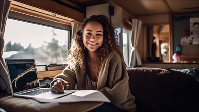 Happy mixed-race young adult female enjoying working remotely inside her RV camper trailer