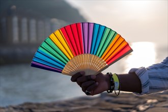 LGBTQ community pride. Hand with fake nails in colors of the rainbow holds rainbow fan