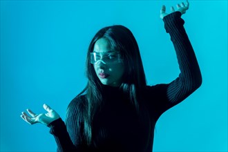 Technology concept. Portrait of woman in futuristic glasses with led light on a blue background