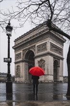 Women with red umbrella in front of the Arc de Triomphe