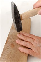 Closeup shot of a woman's hands hammering a nail with a hammer