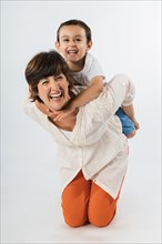 Mother and little son having fun piggybacking. Mother and young son in a funny portrait