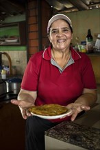 Woman chef smiles and looks at the camera showing a freshly made omelet in her typical Costa Rican food business
