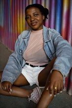 Portrait of Young African American Woman sitting on the floor on a colorful metal wall