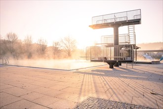 Diving tower at the open-air swimming pool at sunrise in fog