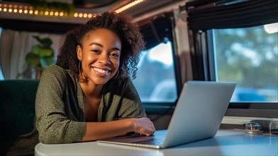 Happy african american young adult female enjoying working remotely inside her RV camper trailer