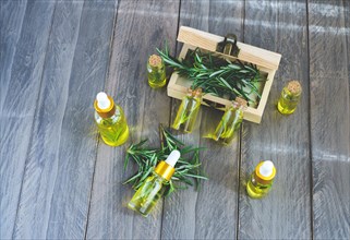 Top view of dropper bottles with rosemary essential oil in a wooden box on a wooden table