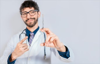 Handsome doctor holding and pointing a syringe isolated. Smiling doctor showing a syringe on isolated background. Doctor and vaccine concept