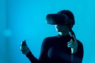Metaverse technology concept. Woman in virtual reality VR glasses on a blue background. Futuristic
