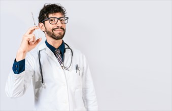 Young doctor holding a syringe isolated. Smiling doctor holding a syringe on isolated background. Doctor and vaccine concept