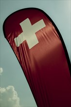 Swiss Banner Flag with Sunlight and Against Sky with Cloud