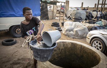Boy draws water from a well on an industrial site