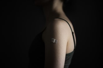 A plaster is stuck on the left upper arm of a woman vaccinated against Corona
