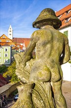View of the naked buttocks of a male stone sculpture across the castle square to the Church of the Visitation of the Virgin Mary