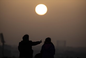 Two people silhouetted against the rising sun in Berlin