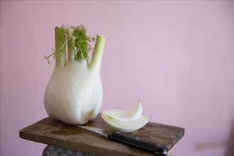 Fresh fennel bulb with knife on a wooden board