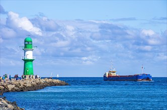Lighthouse and seafaring romance on the west pier while the cargo ship Munin R passes the harbour entrance