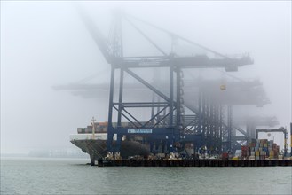 Foggy weather low visibility container ship cranes at quayside