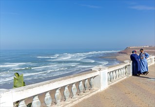 Moroccan men on coastal balustrade next to Atlantic Ocean